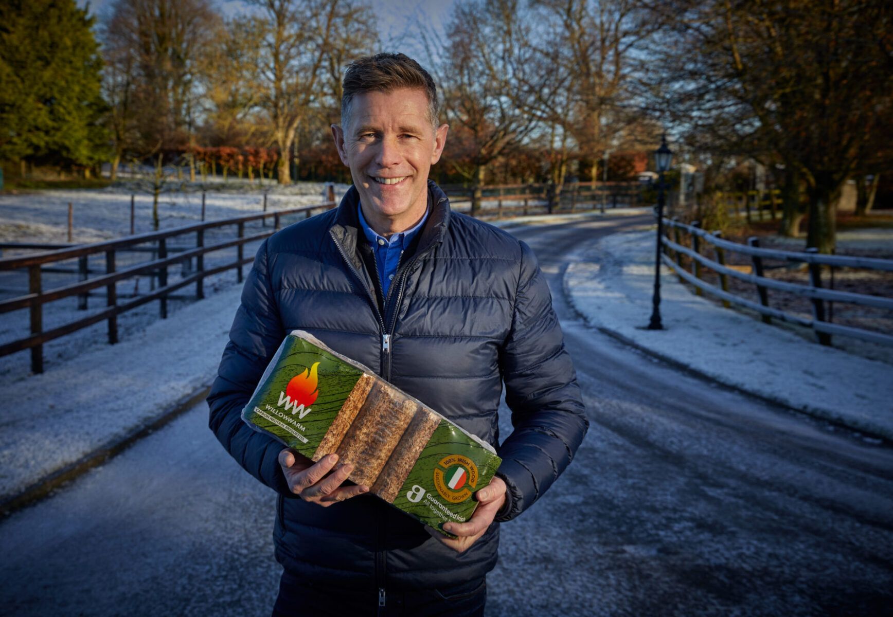 Dermot Bannon holding a bale of WillowWarm Briquettes on a snowy path