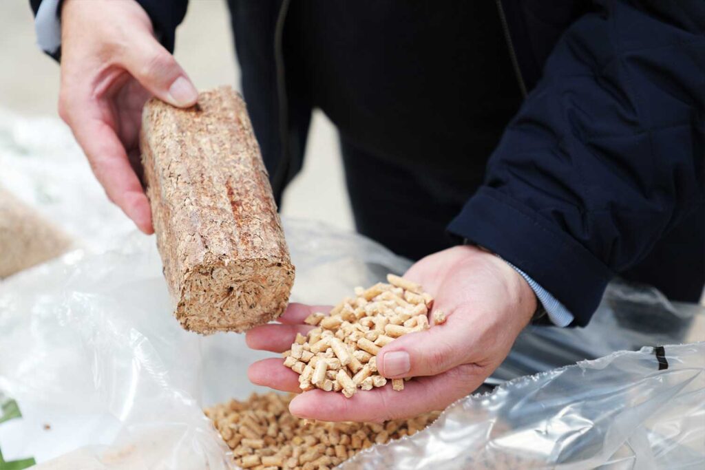 Man's hands holding wood pellets and a WillowWarm Briquette