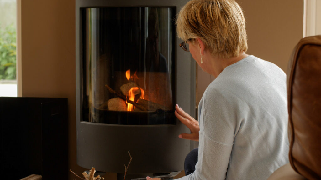 Woman closing door of stove which is burning WillowWarm Briquettes