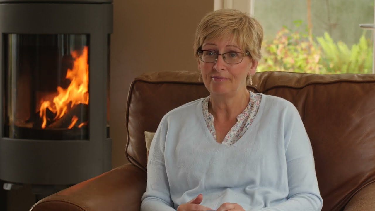 Woman sitting in a brown leather chair with a fire in the background