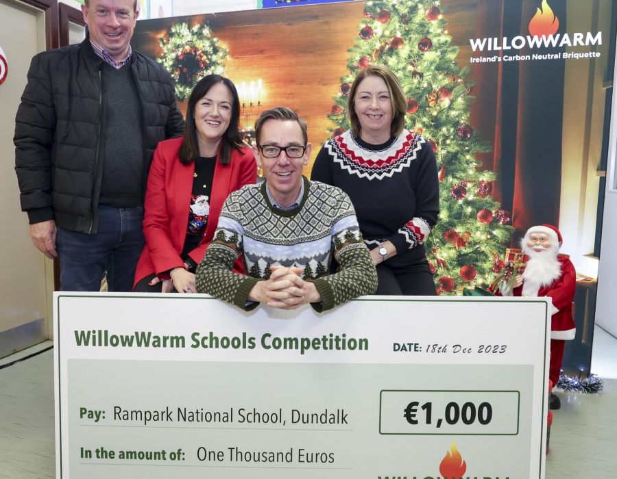 Ryan leaning over a large WillowWarm cheque for €1,000 to the winners of the Ryan Tubridy WillowWarm Schools’ Sustainability Competition with two teachers from the winner school beside him and a representative from WillowWarm