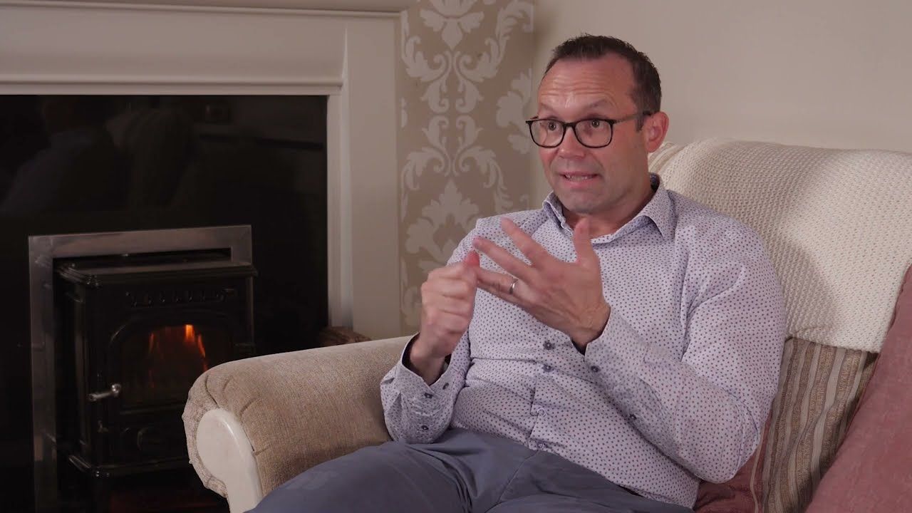 Man sitting in a chair with a fire behind him