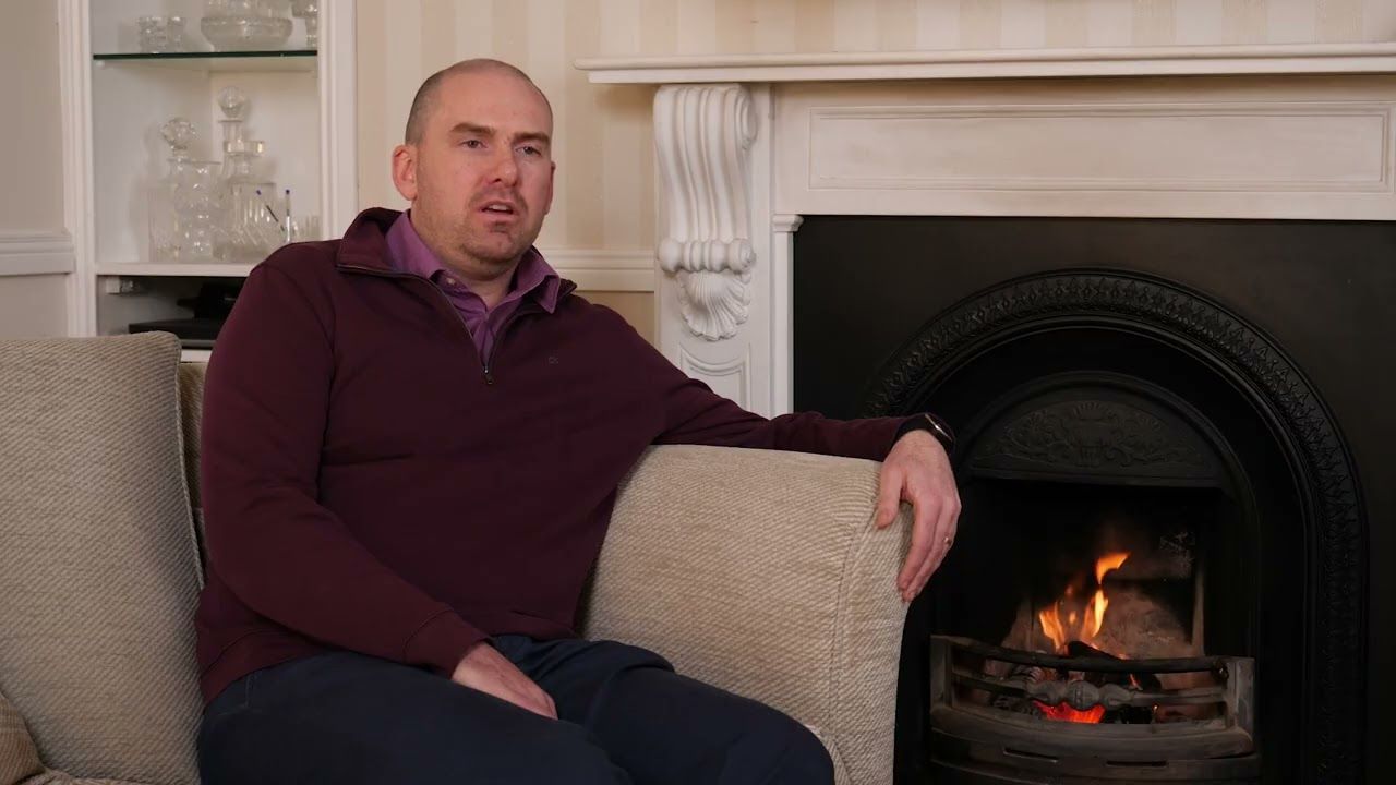 Man sitting in a chair with a fire beside him
